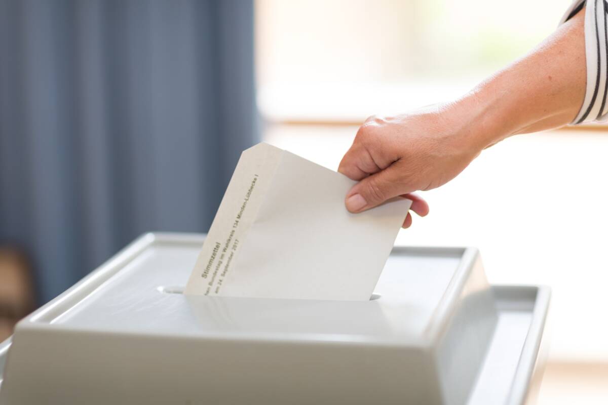 Wahlschein wird von Hand in Wahlurne eingeworfen